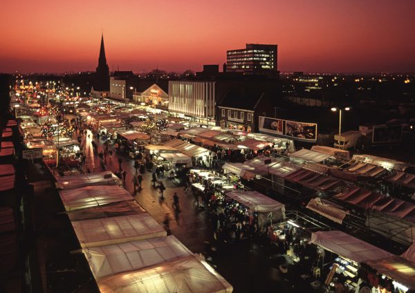 An overhead image of Romford Market at sunset, with a red and orange sky and multiple stalls lit up.